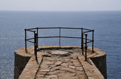 Railing by sea against clear sky