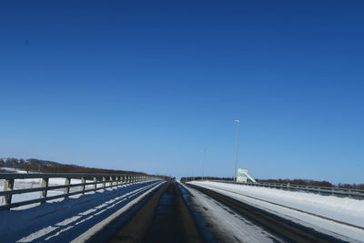 Road against clear blue sky during winter