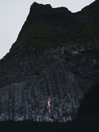 Woman standing on rock formation against mountain