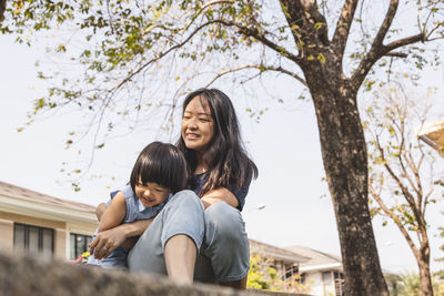 Full length of mother and daughter against trees