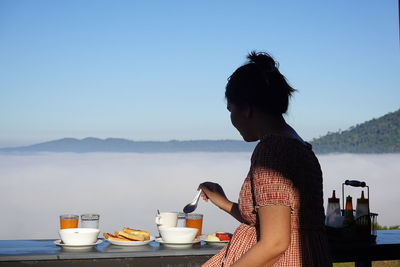 Woman with coffee cup against sky