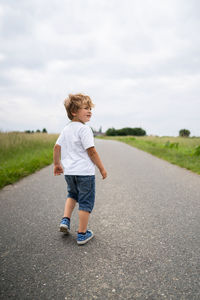 Full length of cute boy on road against sky