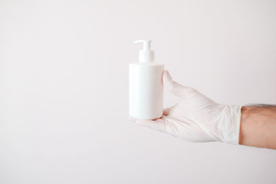 Close-up of hand holding glass against white background