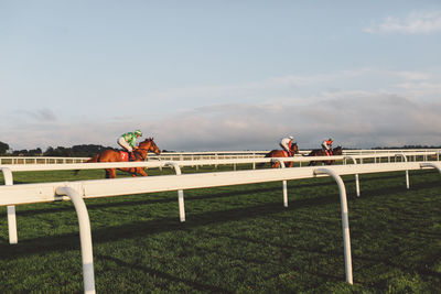 Jockey riding horses at epsom downs racecourse against sky