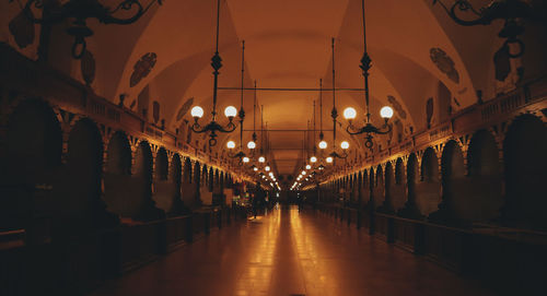 Illuminated lights hanging on ceiling of building at night