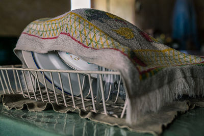 Close-up of dishes in dish rack covered by dish cloth