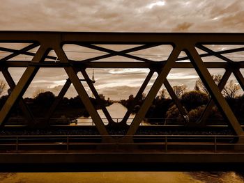 Low angle view of suspension bridge against cloudy sky