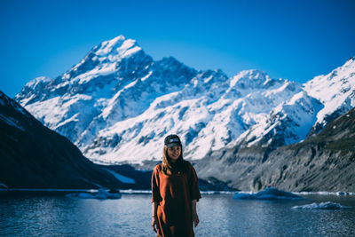 Man standing on snowcapped mountain against blue sky