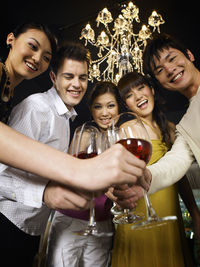 Low angle portrait of happy friends toasting wineglasses at party