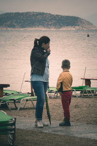 Full length of woman standing with son by lake