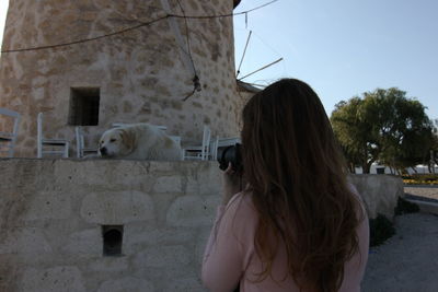 Rear view of woman photographing dog through digital camera