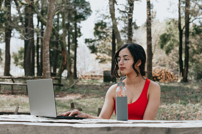 Portrait of young woman using laptop while sitting at park