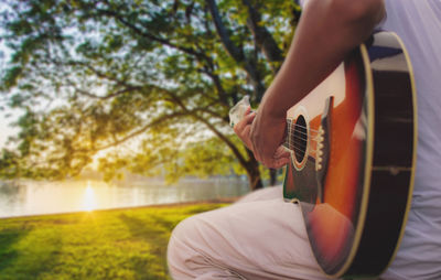 Midsection of man playing guitar