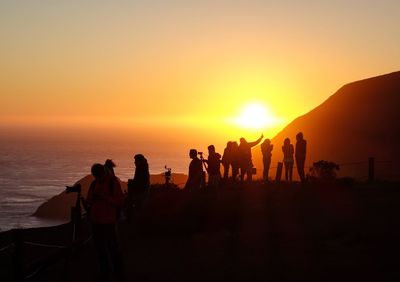 Silhouette people at beach against clear sky during sunset