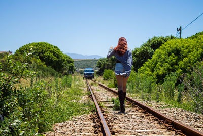 Woman standing by railroad tracks against sky