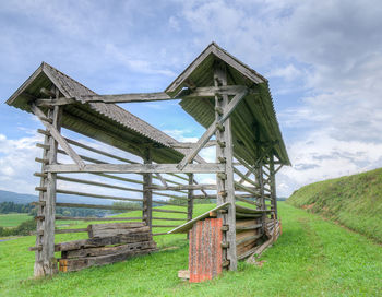 Low angle view of grassy field against cloudy sky