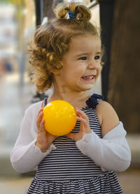 Close-up of cute happy girl holding yellow ball