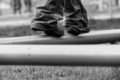 Low section of man walking on metallic railing