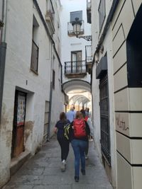 Rear view of people walking on street amidst buildings