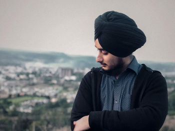 Young man looking at cityscape against sky