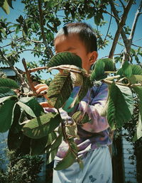 Boy standing by tree