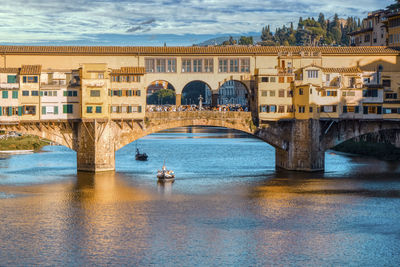 Arch bridge over river against buildings in city