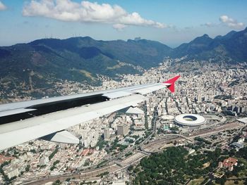 Cropped airplane flying over cityscape and mountains