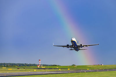 Airplane taking off against rainbow in sky