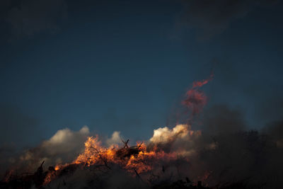 Forest fire against sky at dusk