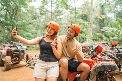 Portrait of smiling friends sitting on road