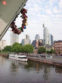 Bridge over river by buildings in city against sky