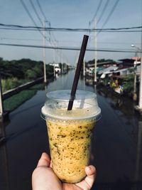 Close-up of hand holding drink against sky