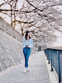 Woman standing on footpath in city