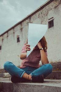 Woman sitting on wall of building