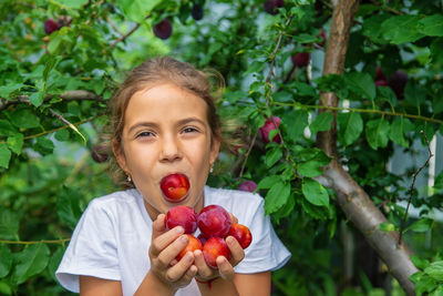 Portrait of girl holding plums in hand