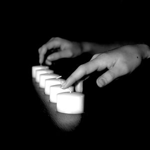 Close-up of hands playing guitar against black background