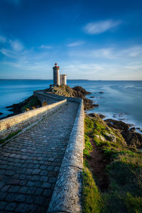 Lighthouse by sea against sky