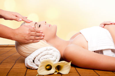 Cropped hands of masseur giving massage to young woman at spa