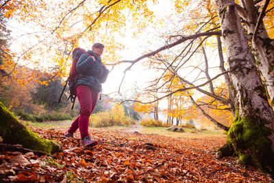 Full length of man standing by tree in forest during autumn