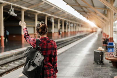 Rear view of woman standing on railroad station platform