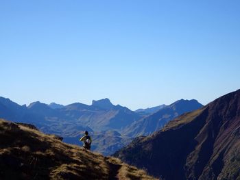 Young woman standing of mountain against clear blue sky