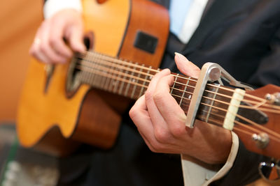 Midsection of man playing acoustic guitar