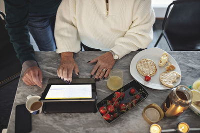 High angle view of senior couple using digital tablet while sitting by dining table in living room