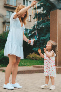 Full length of mother and girl standing outdoors