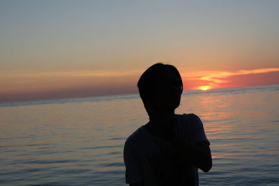 Silhouette man standing at beach during sunset