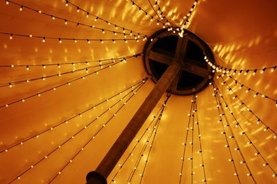 Low angle view of illuminated string lights hanging on ceiling in tent