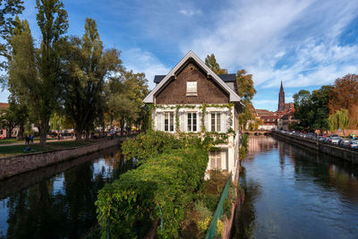 Canal amidst trees and buildings against sky