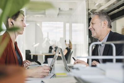 Happy businessman having discussion with colleague at desk