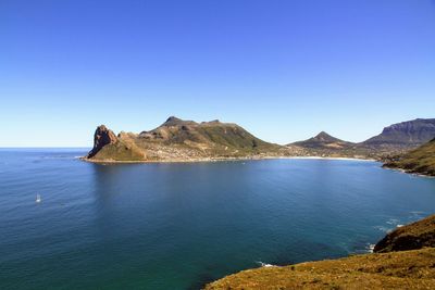 Scenic view of sea and mountains against clear blue sky