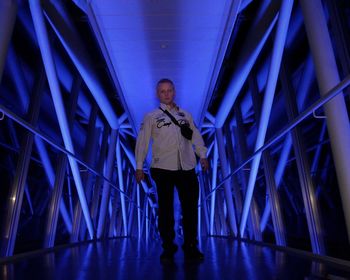 Low angle view portrait of man standing against illuminated built structure